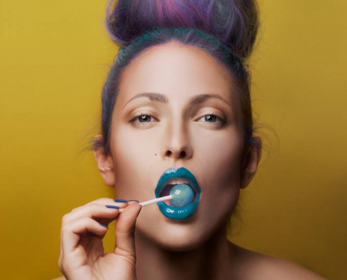 Make up Artist. Model mit blauen Lippen und Haaren auf gelben Hintergrund.