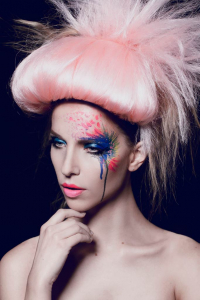 Model mit Makeup in blau und rot, sowie Haarteilen in rosa