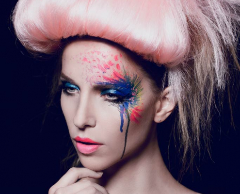 Model mit Makeup in blau und rot, sowie Haarteilen in rosa