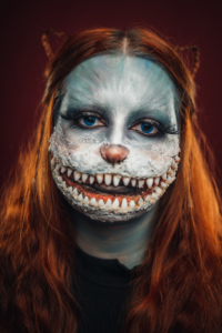Maske süßes Monster mit breiter Grimasse, blauen Augen, langen Wimpern und roten Haaren.